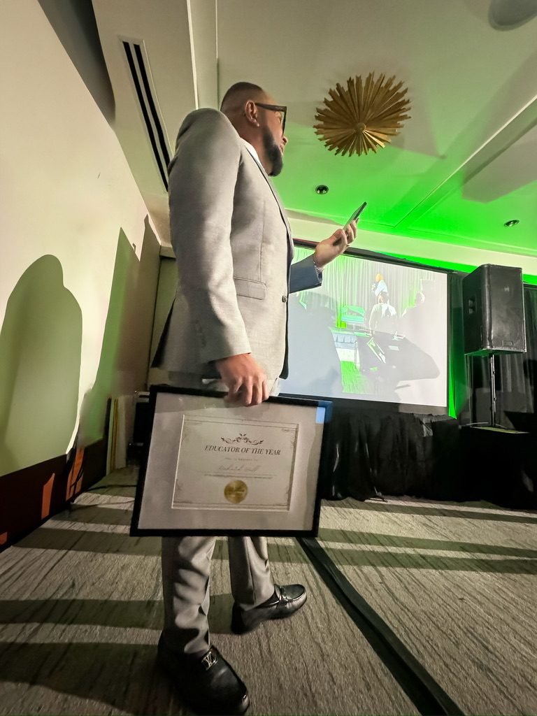 Richard Hall Jr. holding his Educator of the Year certificate