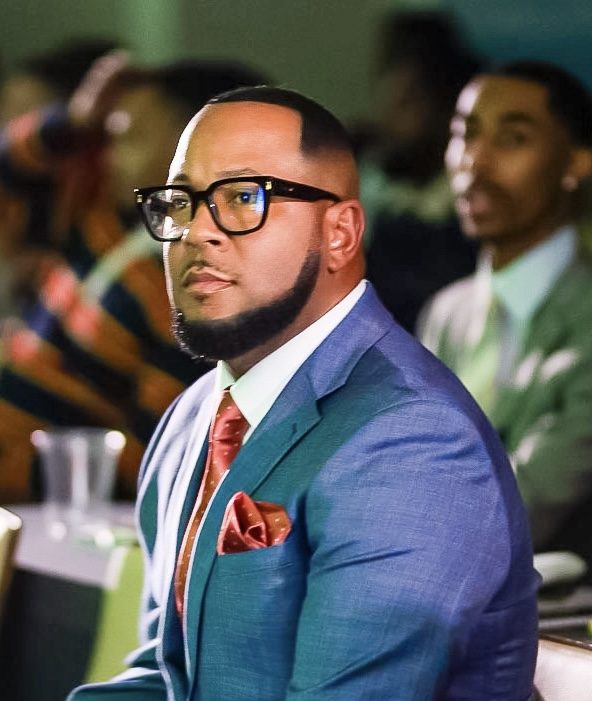 Richard Hall Jr. seated at an event in a blue suit